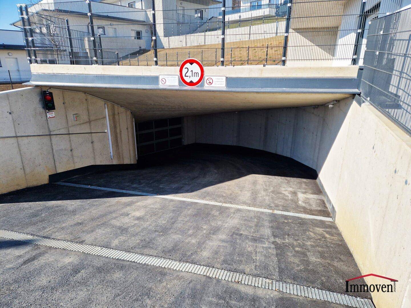 Einfahrt zur Tiefgarage mit Höhenbegrenzung und moderner Gestaltung, gut zugänglich.