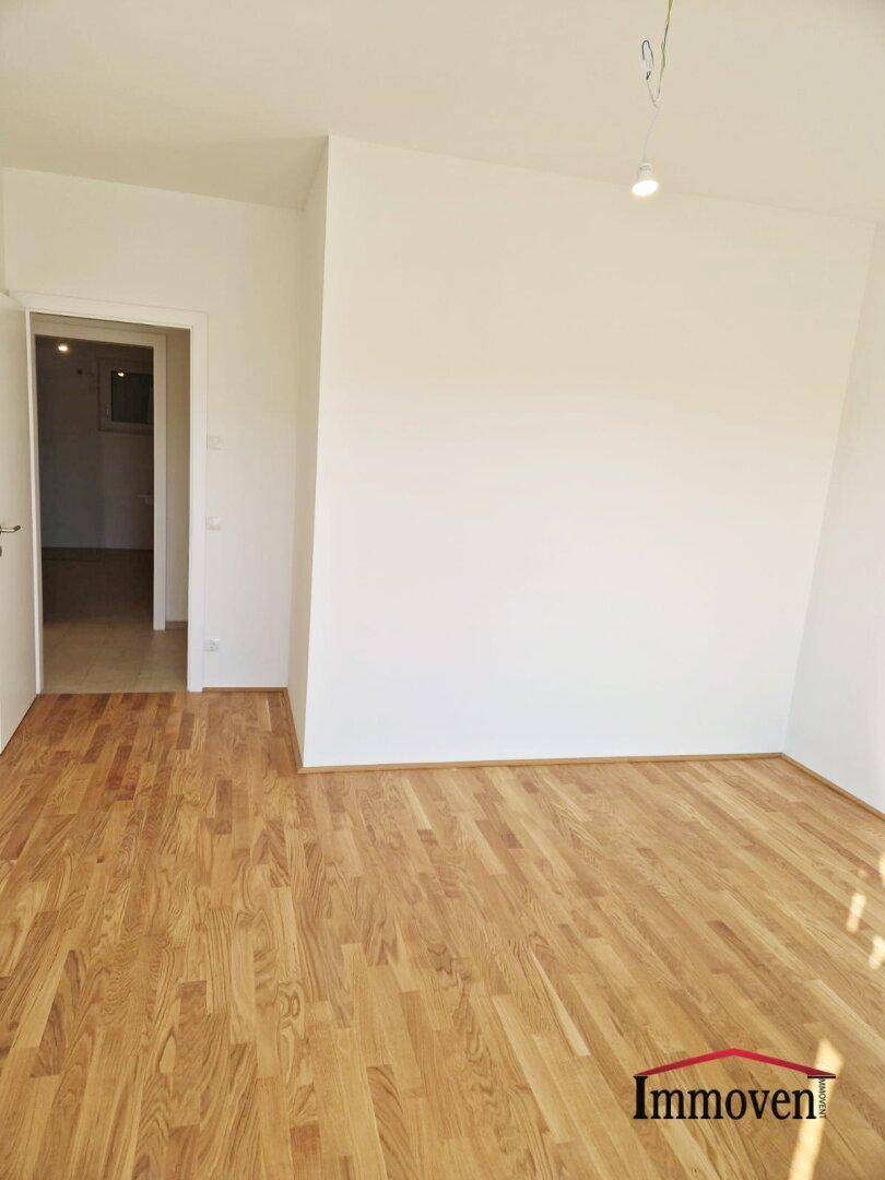 Unmöblierter Raum mit Parkettboden und Zugang zu einem weiteren Zimmer, vielseitig nutzbar.