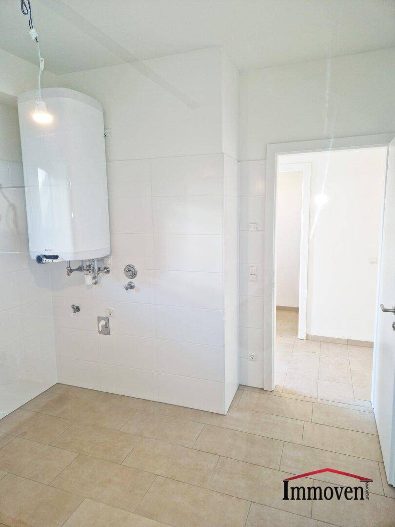 Funktionaler Hauswirtschaftsraum mit Warmwasserbereiter und gefliesten Wänden, ideal für Technik.