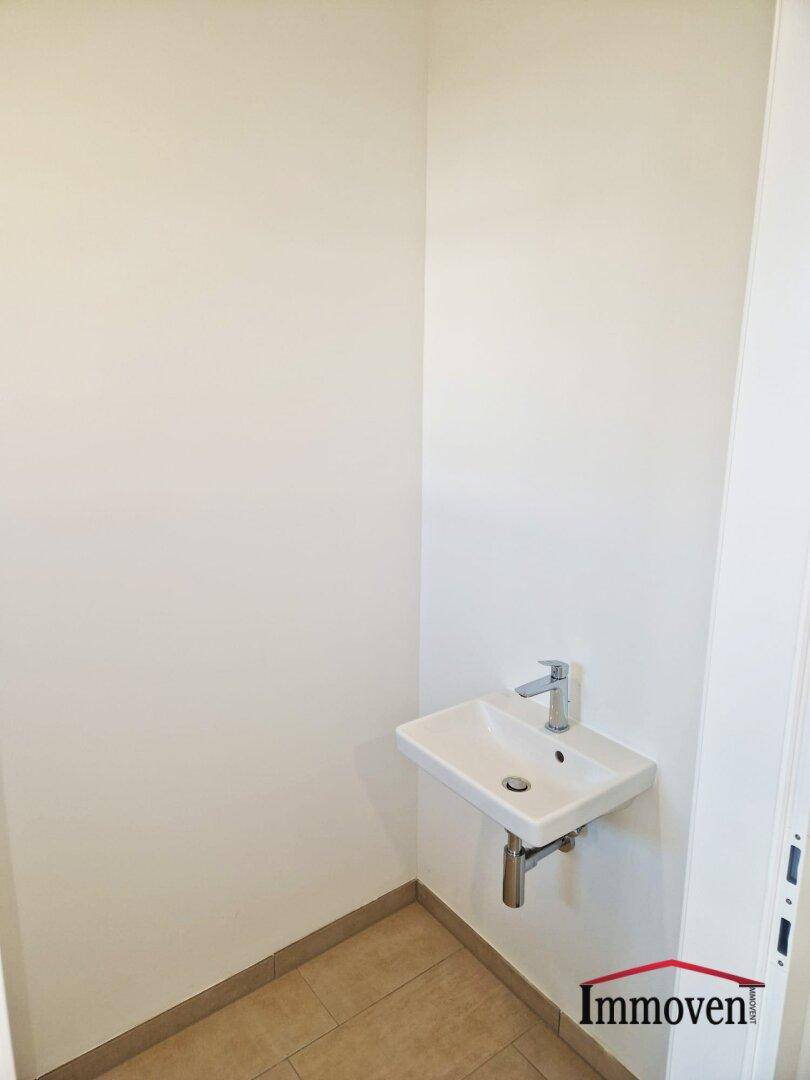 Kleines Gäste-WC mit modernem Einzelwaschbecken und hellen Fliesen.