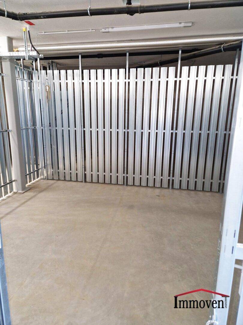 Abgetrennter Lagerraum mit Metallgittern und Betonboden, ideal für zusätzlichen Stauraum.
