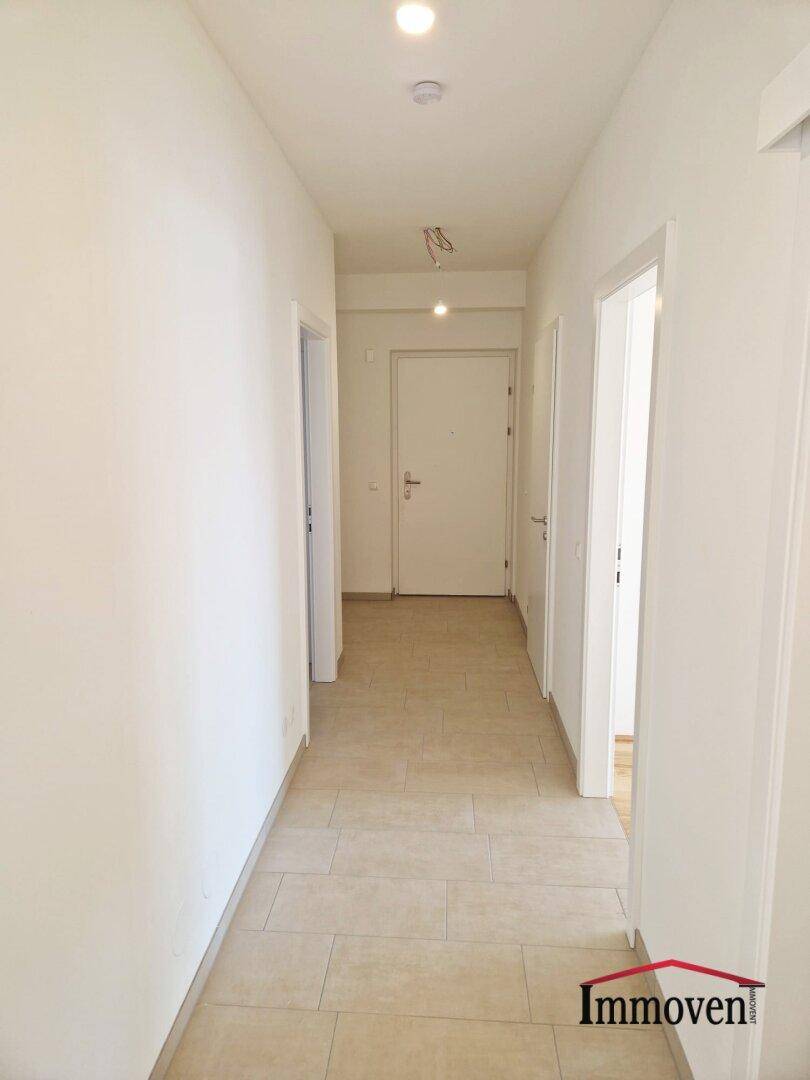 Langer, heller Flur mit Fliesenboden und Zugang zu verschiedenen Zimmern der Wohnung.