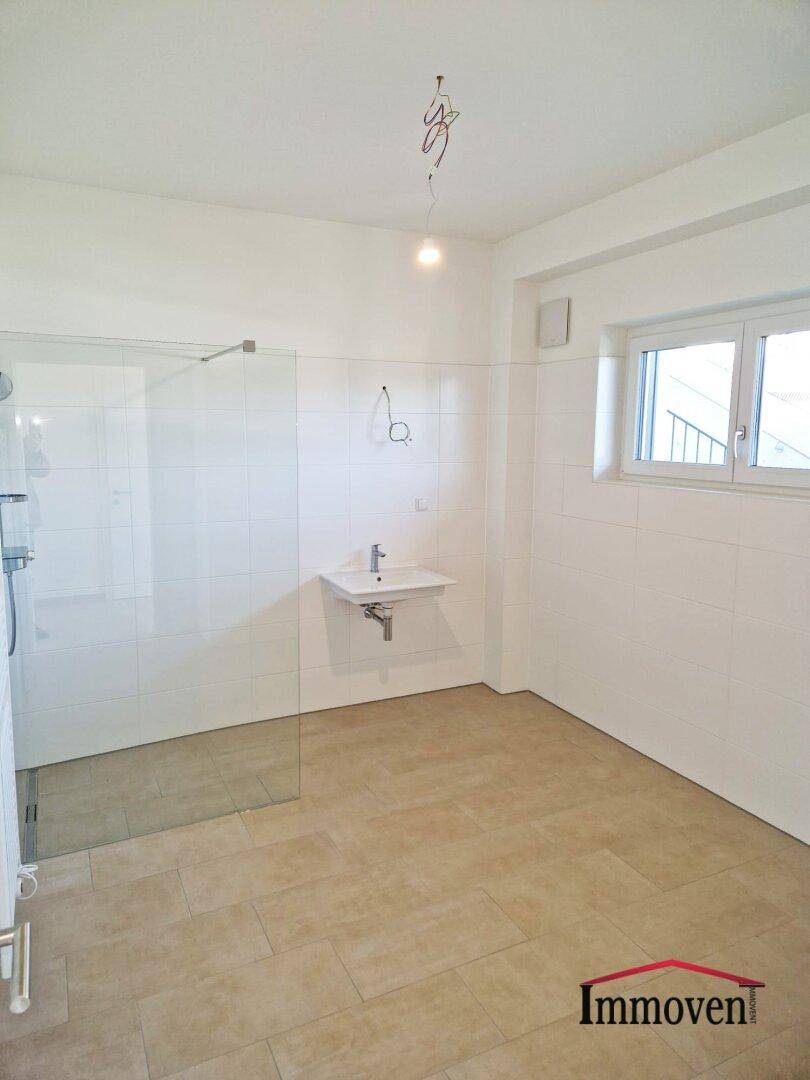 Modernes Badezimmer mit begehbarer Dusche, Waschbecken und Fenster für Tageslicht.