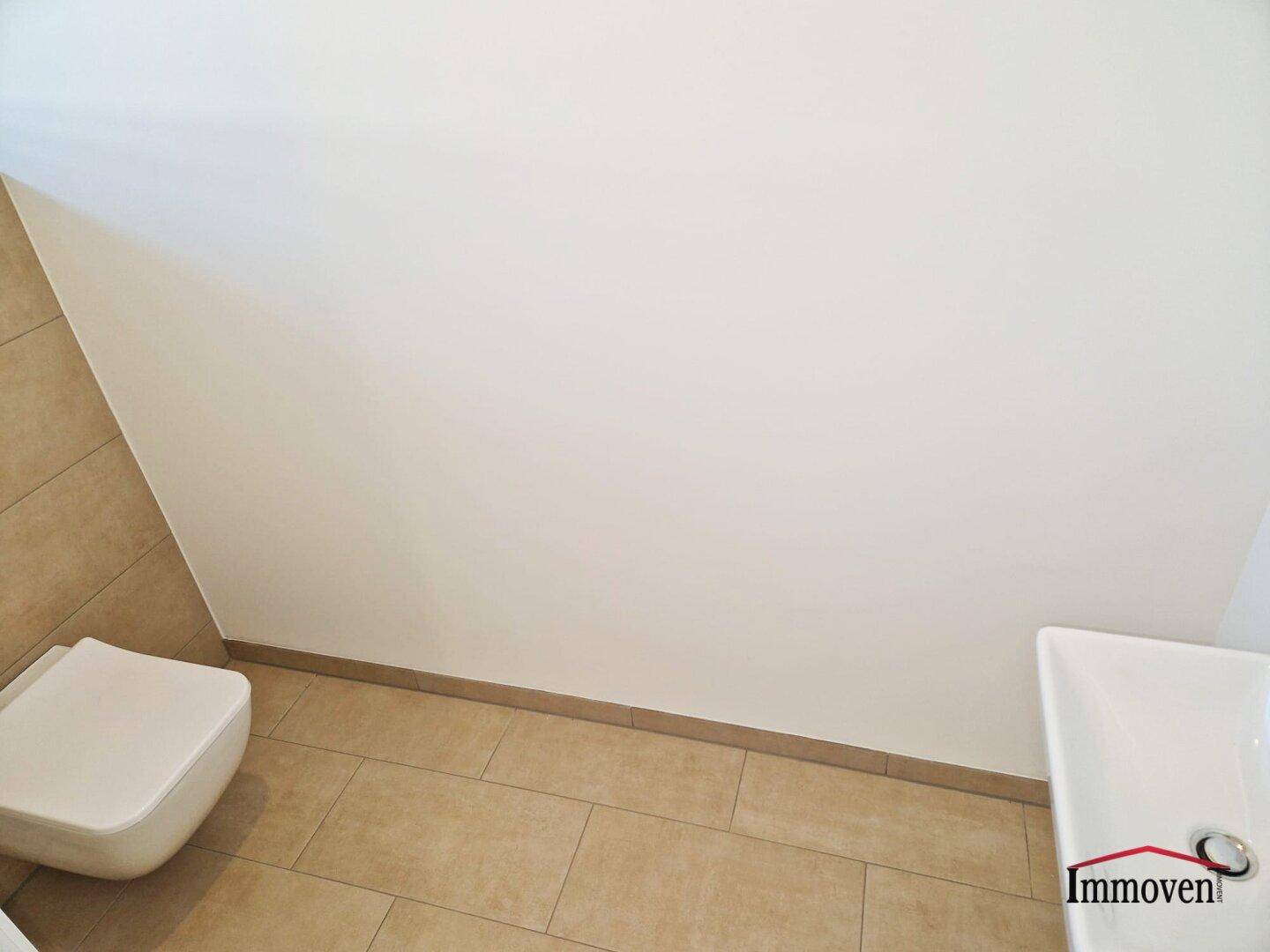 Kleines Badezimmer mit Wand-WC und Waschbecken, ausgestattet mit modernen Fliesen.
