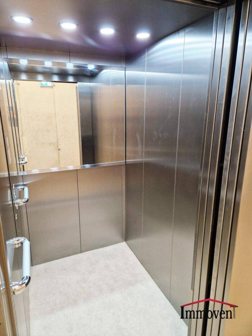 Moderner Aufzug mit Edelstahlverkleidung und Spiegelfläche im Inneren.