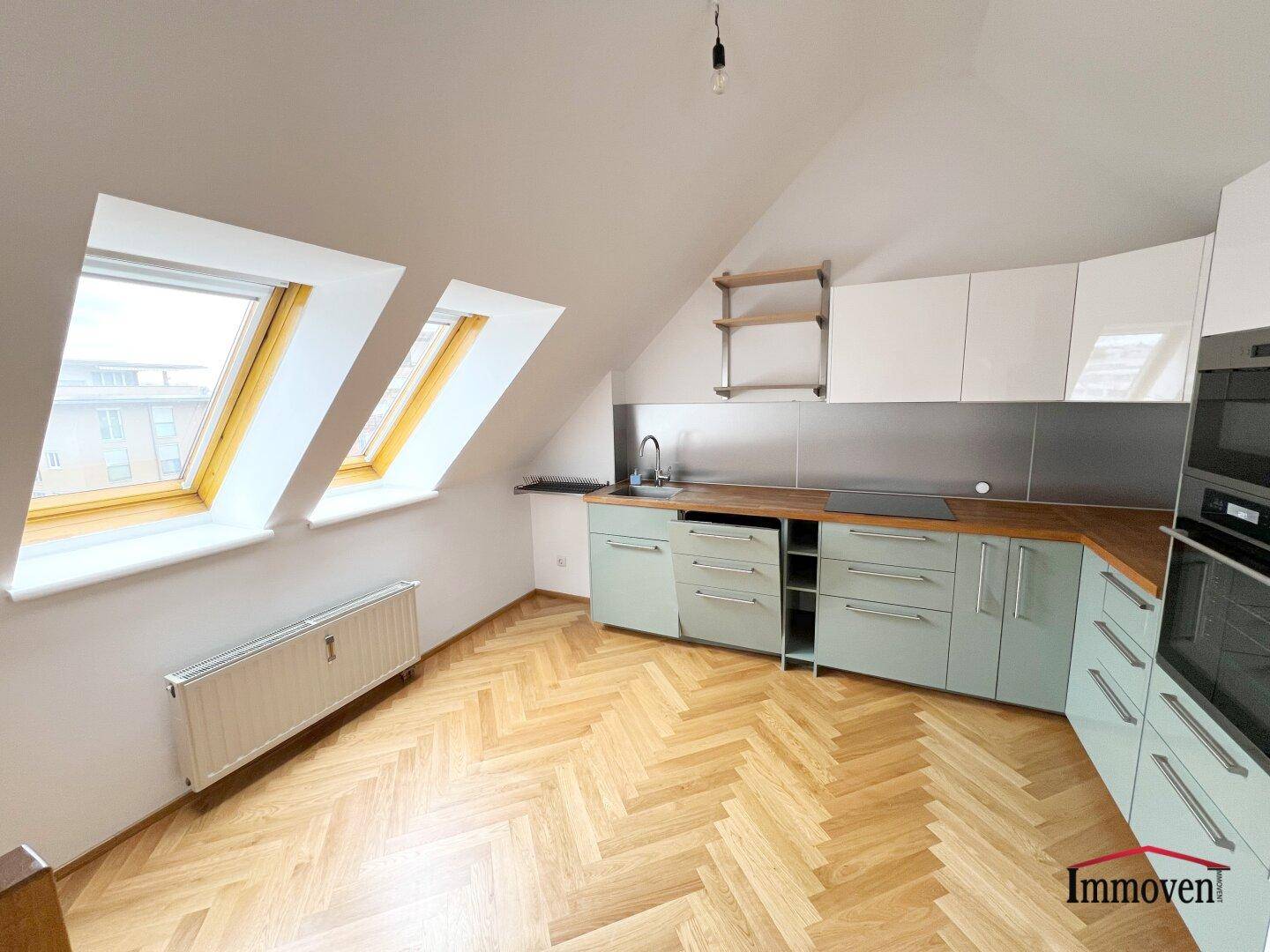 Helle Dachgeschossküche mit Parkettboden, Dachfenstern und moderner Ausstattung.