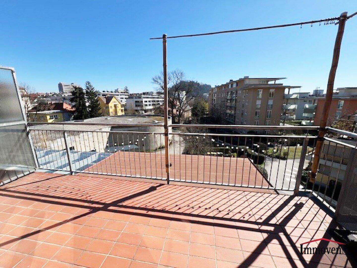 Große Dachterrasse mit Fliesenboden und weitem Blick über die Stadt und die Umgebung.