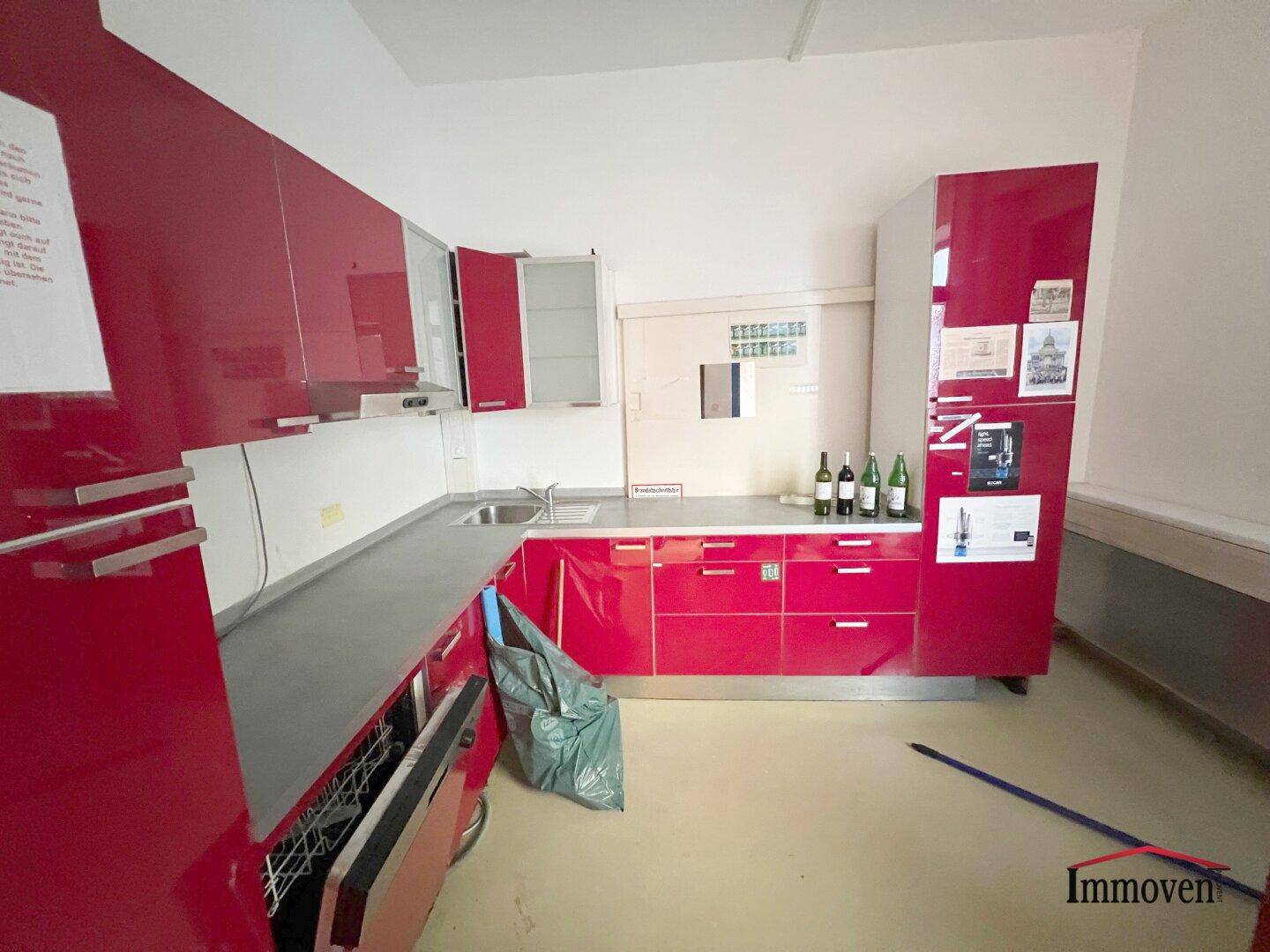 Moderne Küche mit leuchtend roten Hochglanzschränken, Spülmaschine und viel Stauraum.
