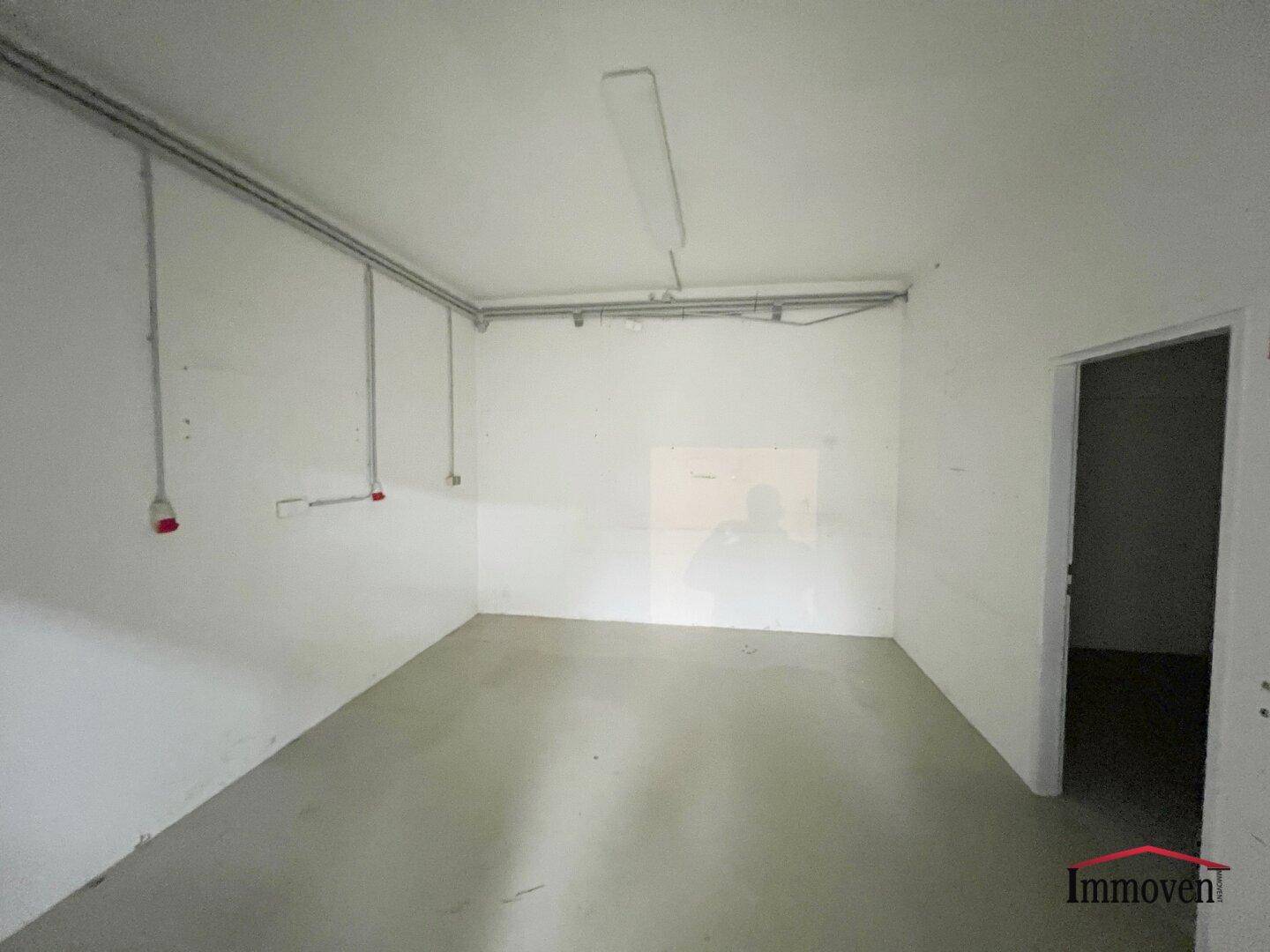 Leerer Abstellraum mit weißen Wänden und einfacher Beleuchtung, ideal für Lagerzwecke.