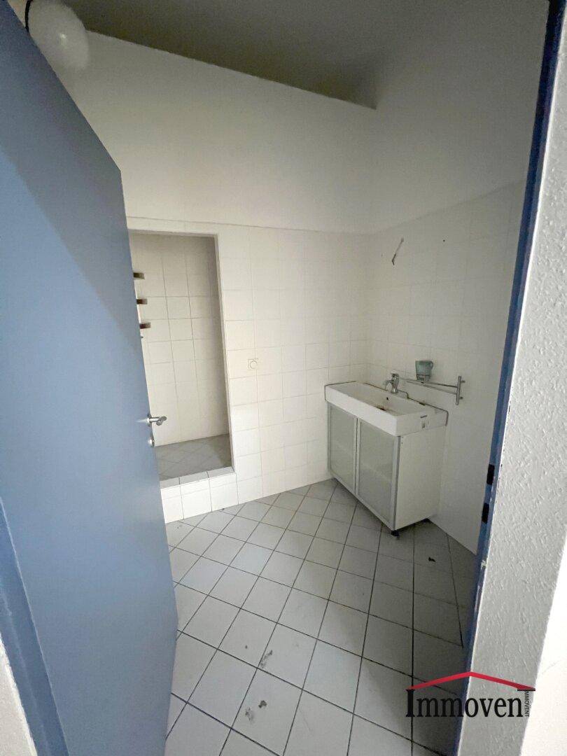 Badezimmer mit gefliestem Boden, zwei Waschbecken und einer Duschkabine im Hintergrund.