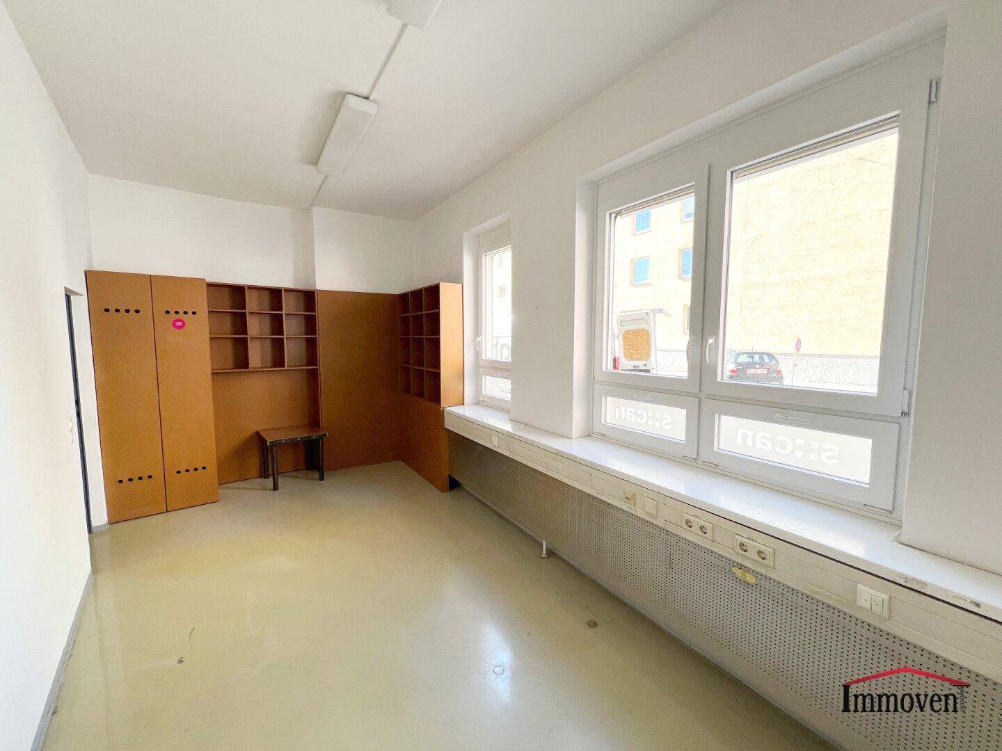 Büroraum mit Schließfächern und Regalen, sowie großen Fenstern mit Blick nach draußen.