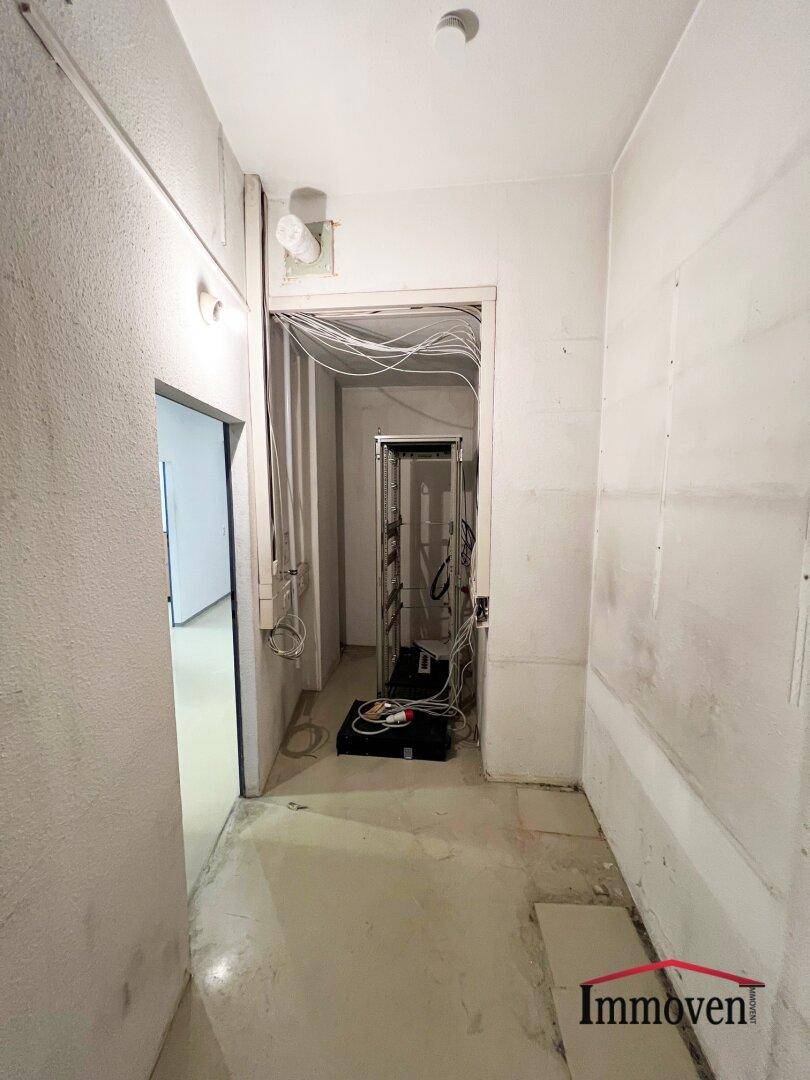 Technikraum mit sichtbaren Kabeln und einem Serverschrank, der auf eine Infrastruktur hinweist.