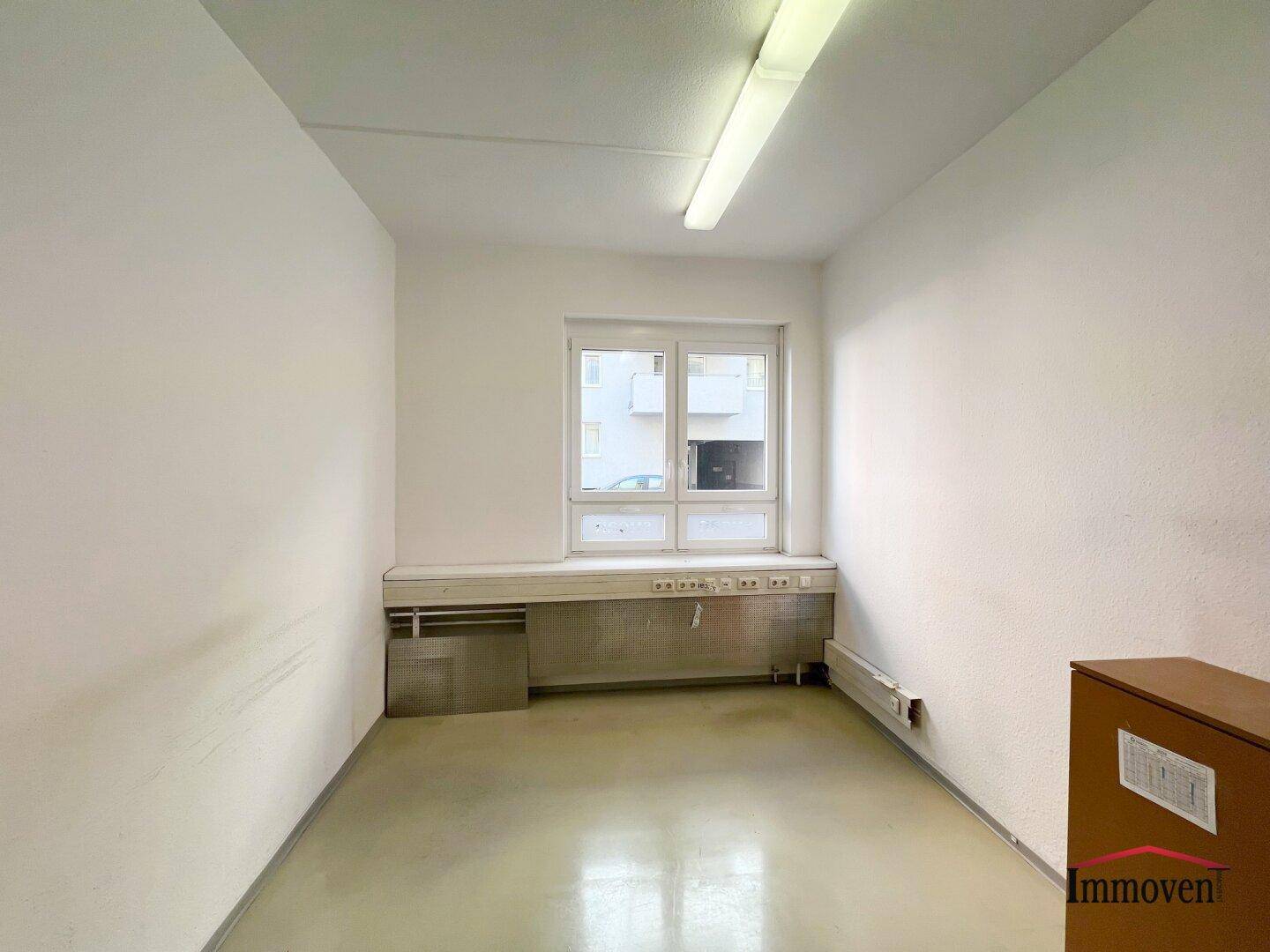 Kleiner Büroraum mit einem Fenster und einem Heizkörper unter der Fensterbank.