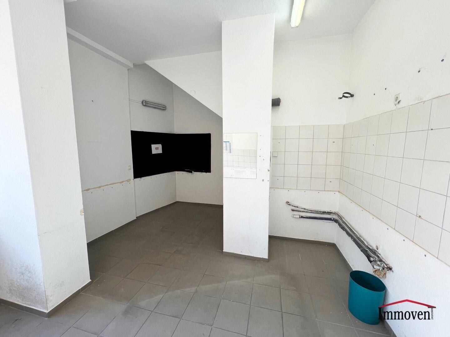 Raum mit Fliesenboden, gefliesten Wänden und sichtbaren Leitungen, ideal für eine Küche.