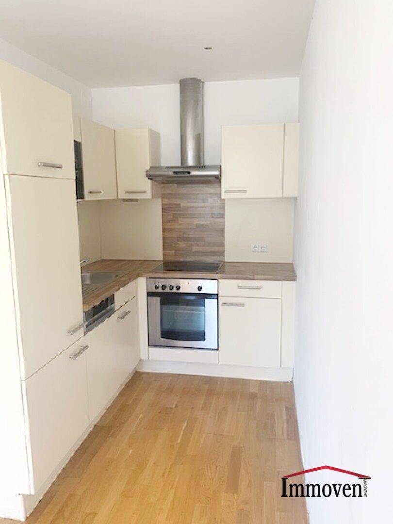 Funktionale Einbauküche mit hellen Schränken, integriertem Backofen und Dunstabzugshaube.