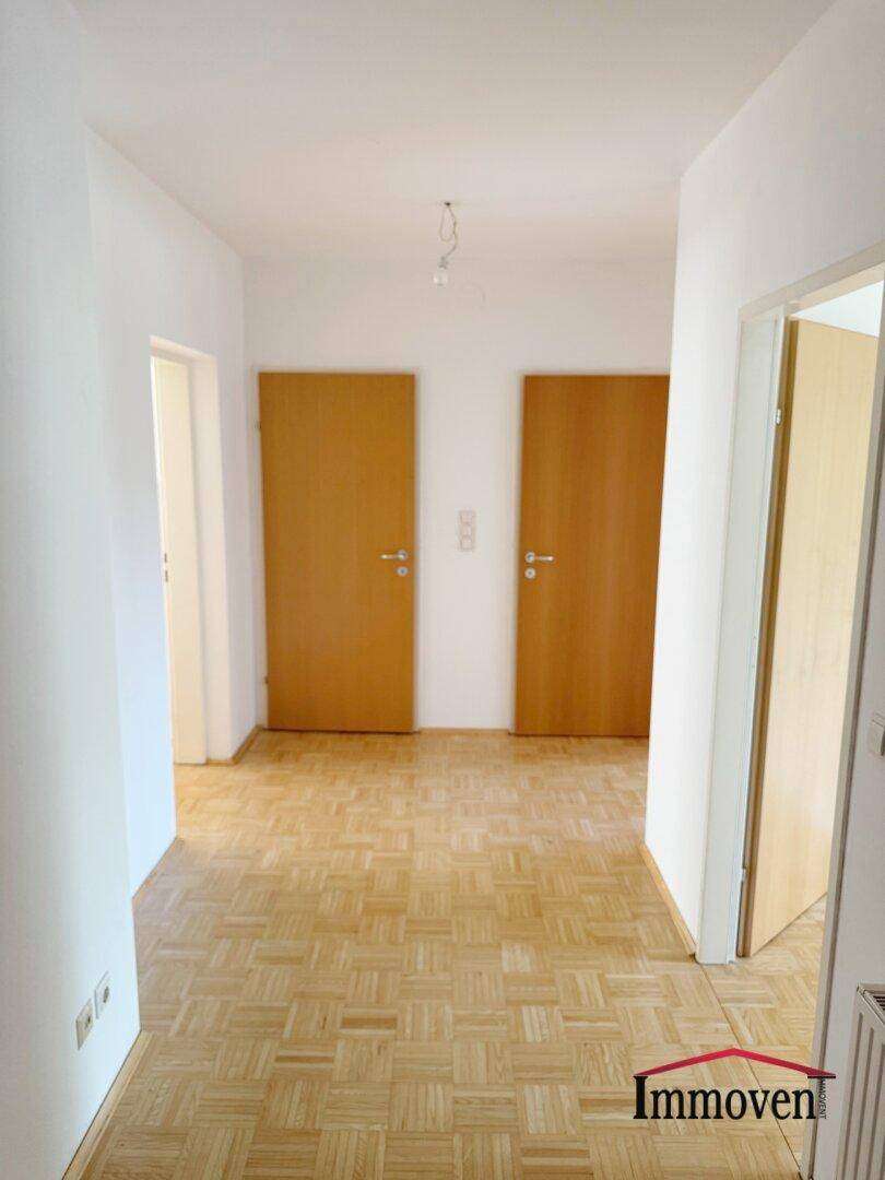 Heller Flur mit Parkettboden und mehreren Türen, der verschiedene Räume miteinander verbindet.