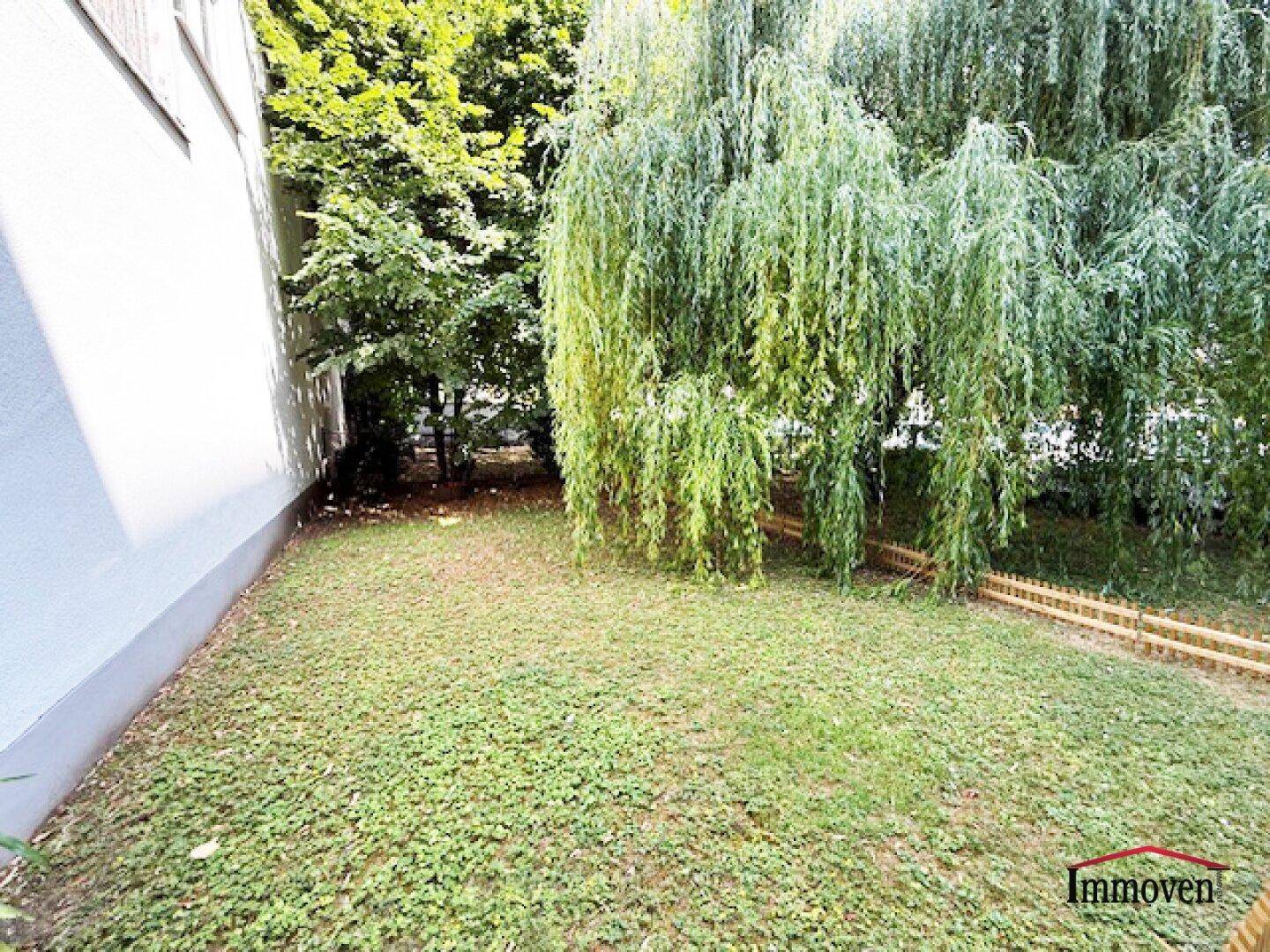 Grüner Gartenbereich mit üppigen Bäumen und Rasenfläche, bietet eine ruhige Oase.