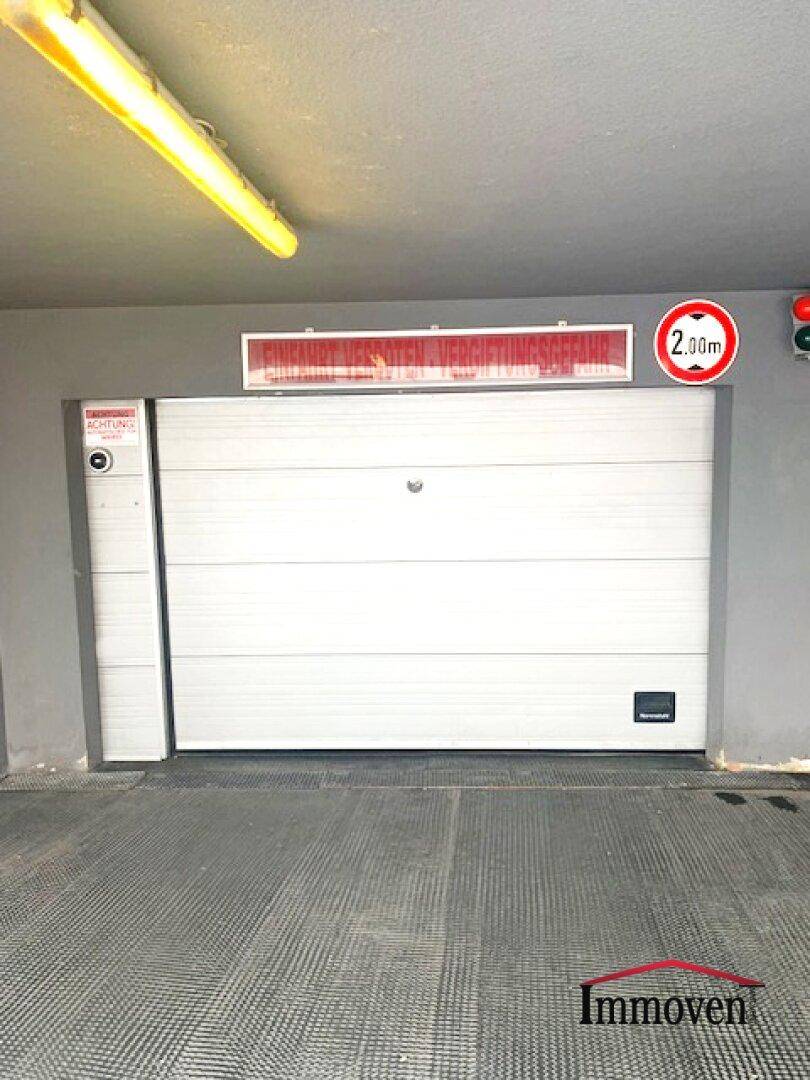 Weiße Garagentür mit Höhenbegrenzung von 2,00m und Einfahrtsverbotsschild in der Tiefgarage.