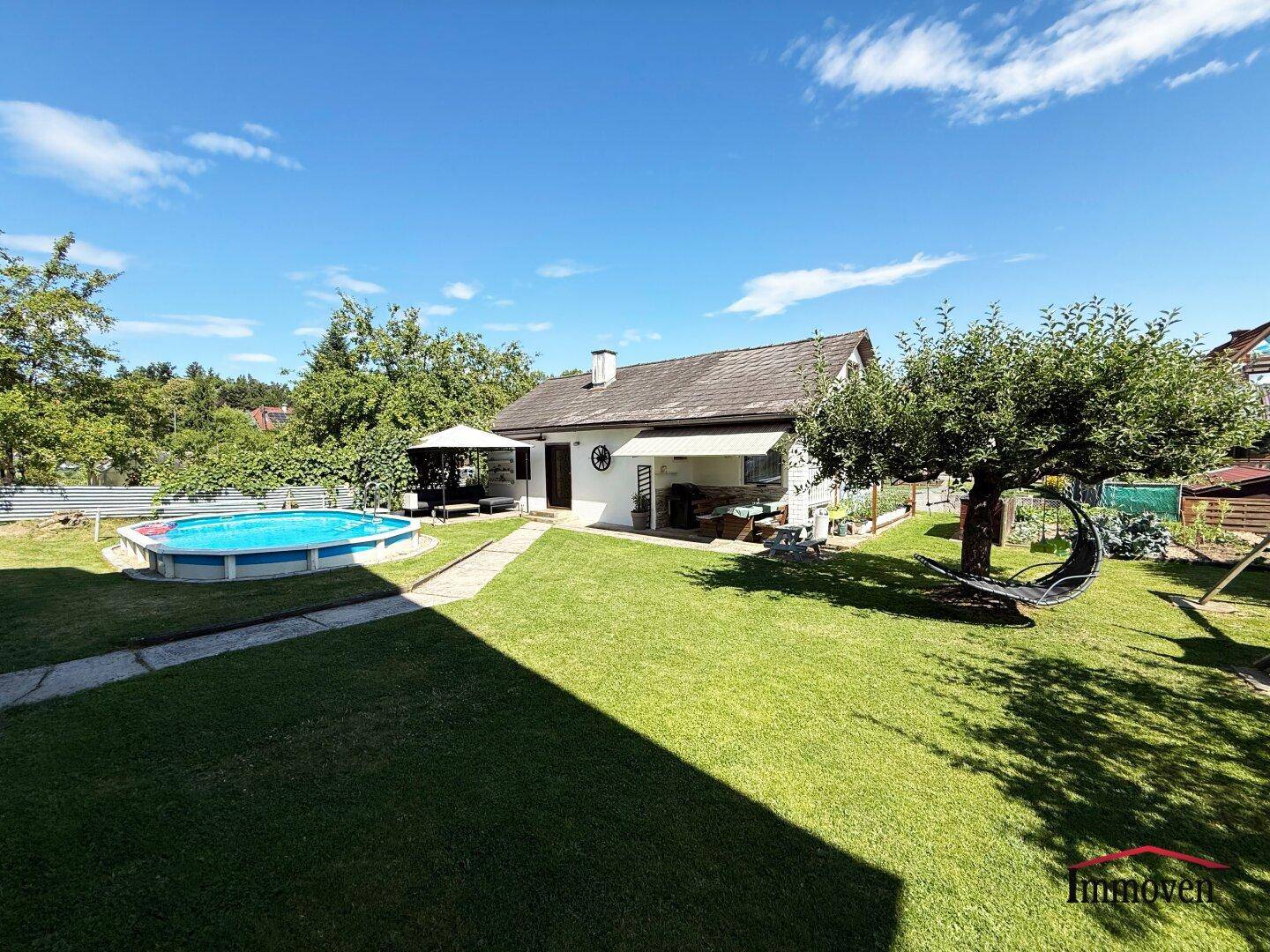Großer, gepflegter Garten mit Aufstellpool und viel Grünfläche unter blauem Himmel.