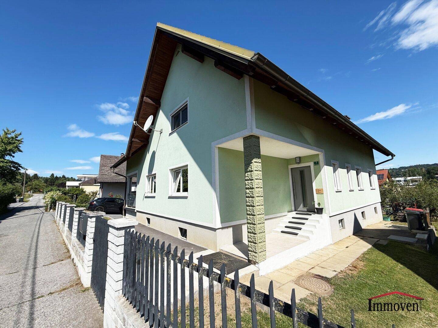 Vorderansicht des Einfamilienhauses mit gepflegtem Vorgarten und Zaun.