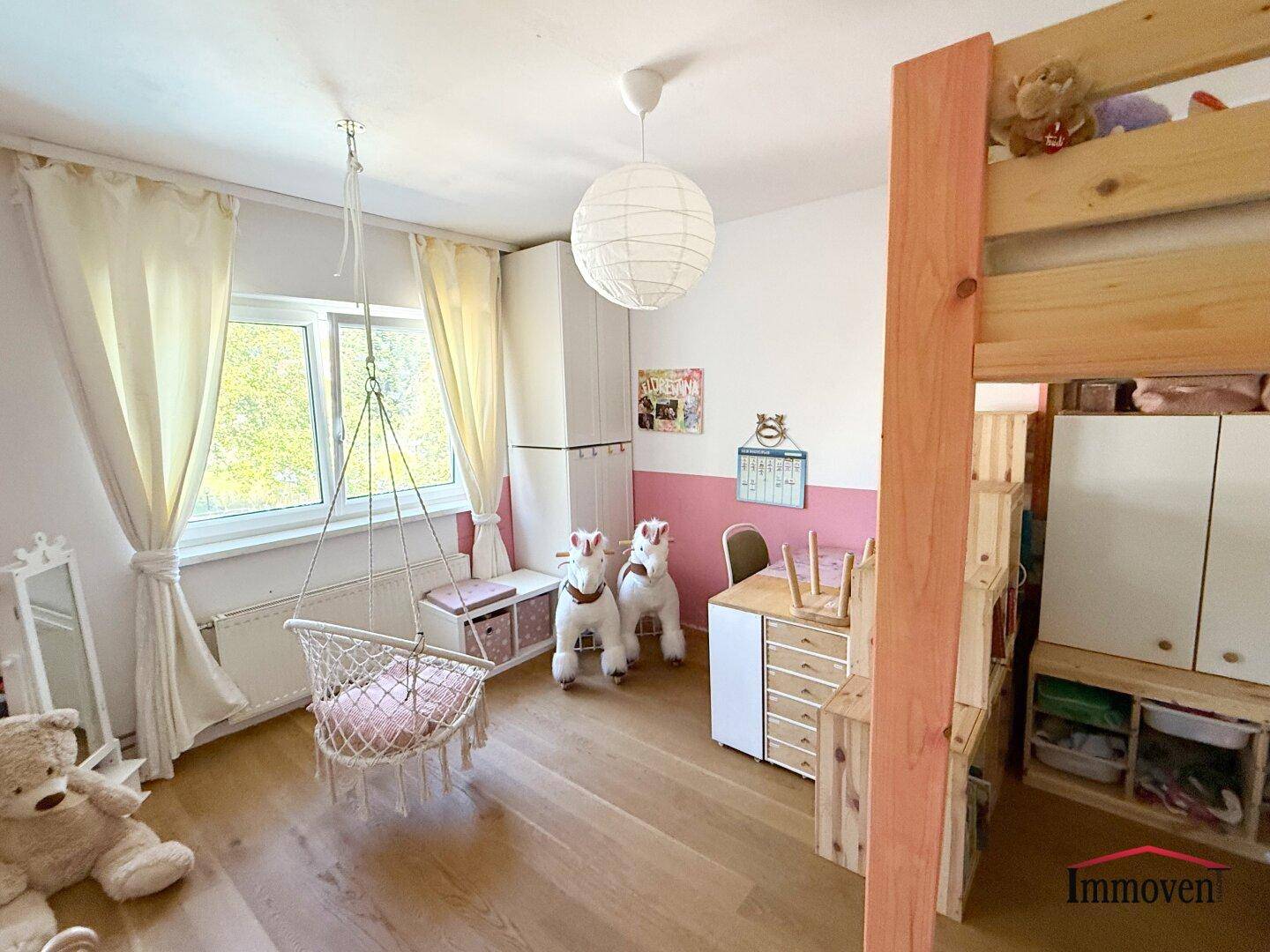 Helles Kinderzimmer mit Holzboden, Schaukelstuhl und Hochbett.