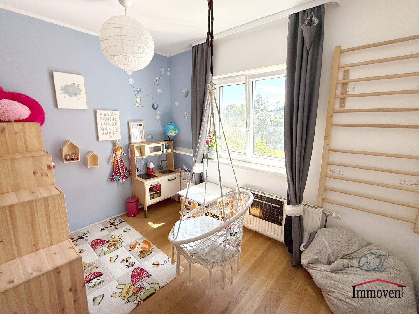 Freundliches Kinderzimmer mit Holzboden, Spielbereich und Kletterwand.