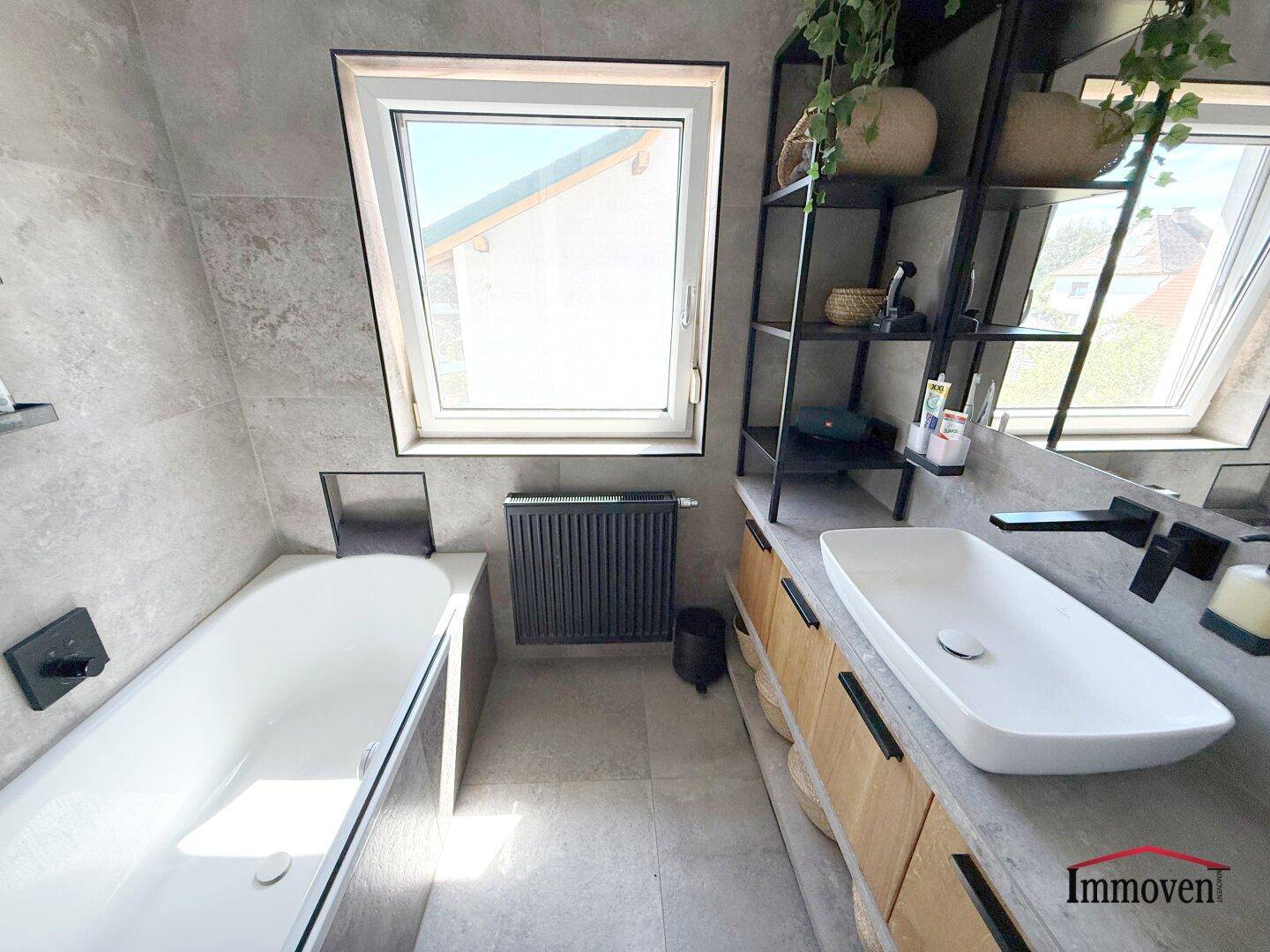 Modernes Badezimmer mit Badewanne, Einzelwaschbecken und Dachfenster.
