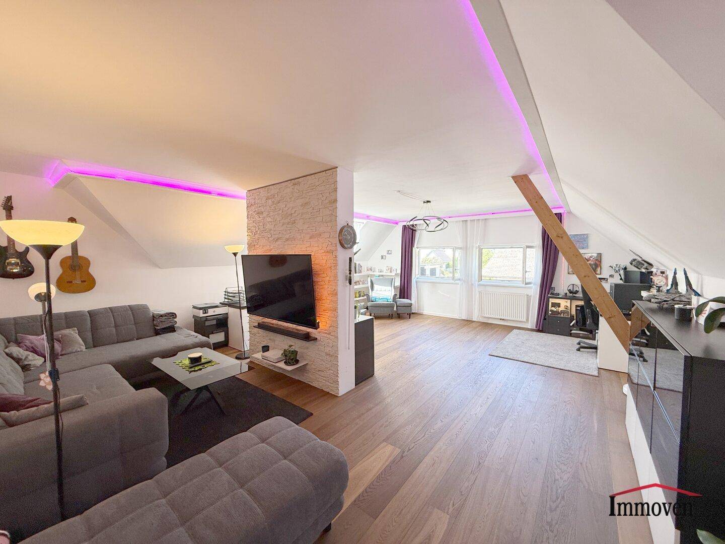 Geräumiges Wohnzimmer im Dachgeschoss mit Holzboden und indirekter Beleuchtung.