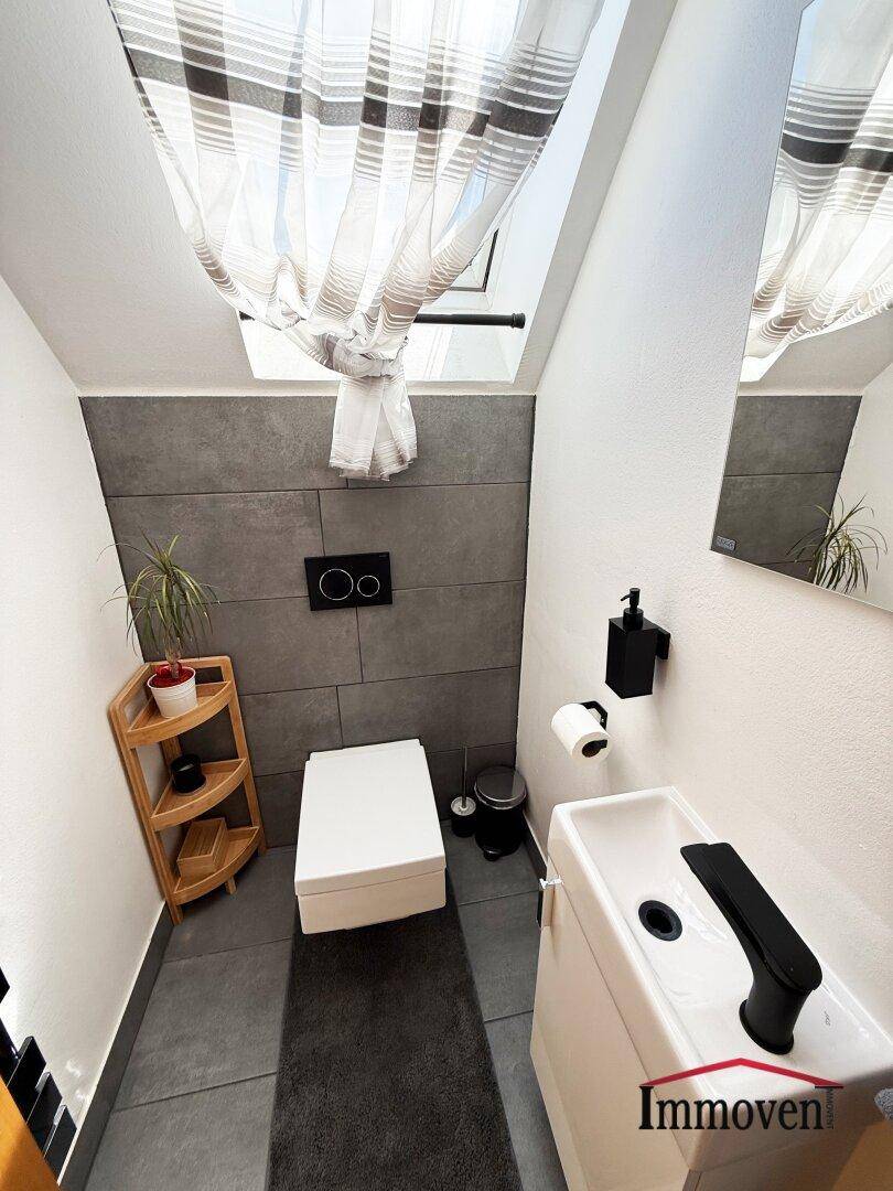 Modernes Gäste-WC im Dachgeschoss mit Dachfenster und dunklen Fliesen.
