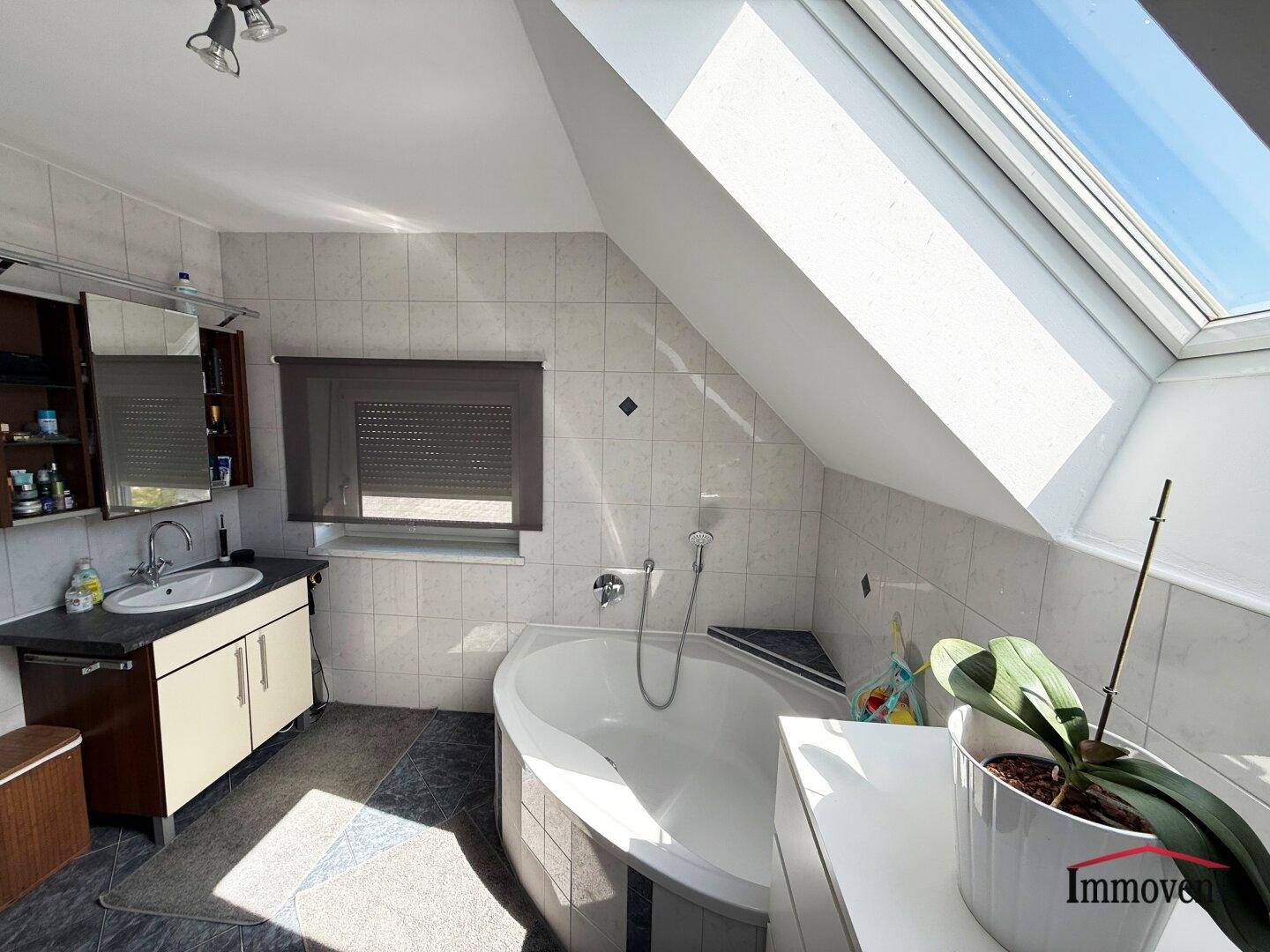 Geräumiges Badezimmer im Dachgeschoss mit Badewanne, Spiegelschrank und Dachfenster.
