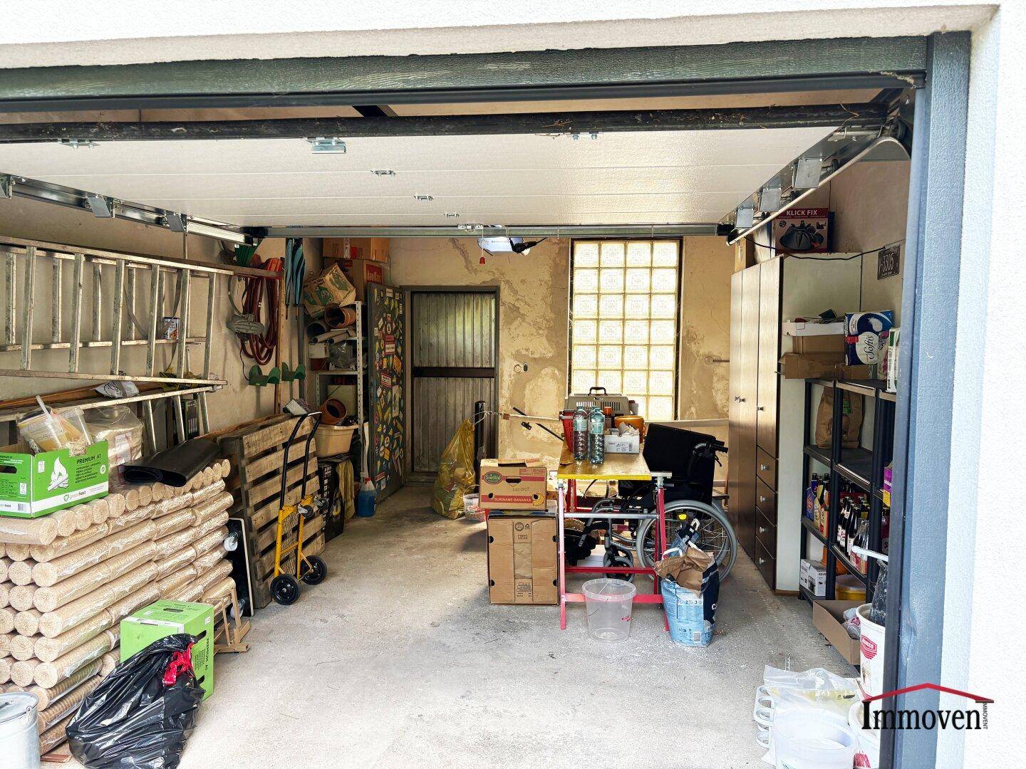 Geräumige Garage mit Betonboden, Stauraum und einem Fenster aus Glasbausteinen.