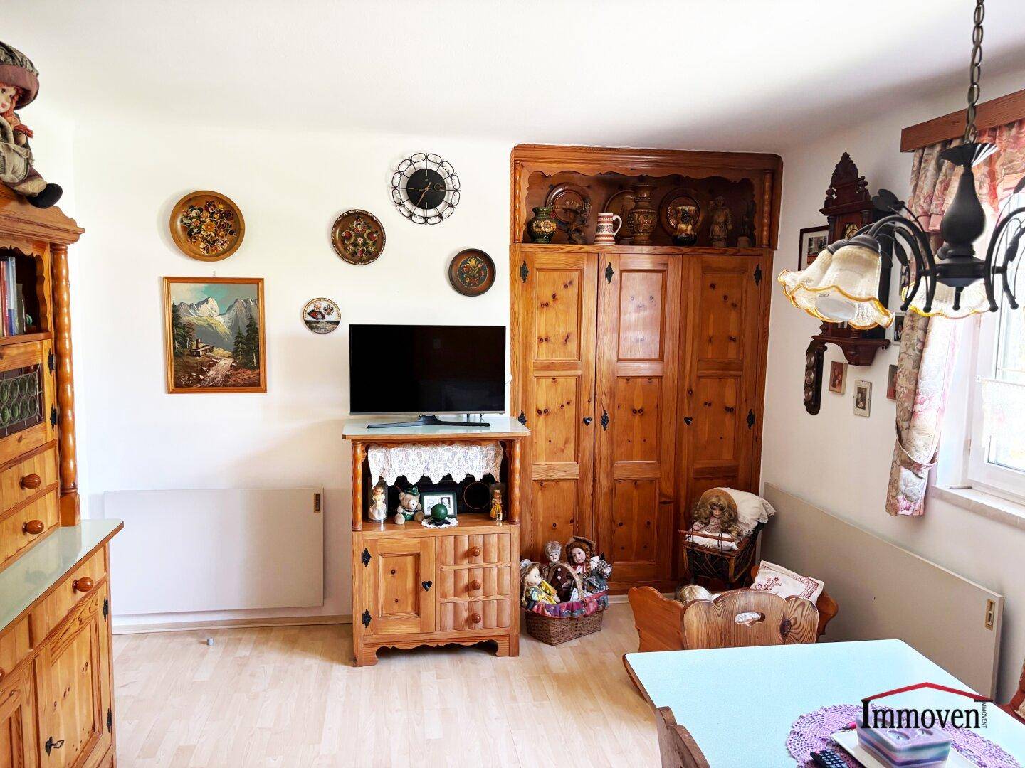 Wohnbereich mit traditionellen Holzmöbeln, einem Fernseher und dekorativen Wandtellern.