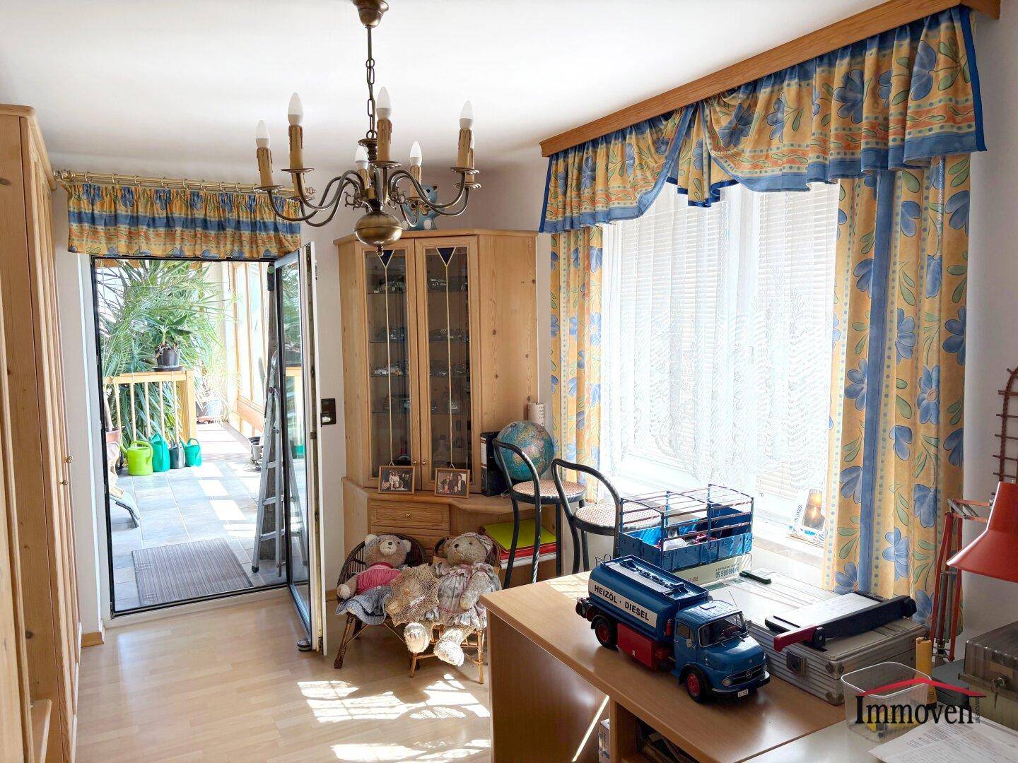 Arbeitszimmer mit Schreibtisch, traditionellen Möbeln und Zugang zum hellen Wintergarten.