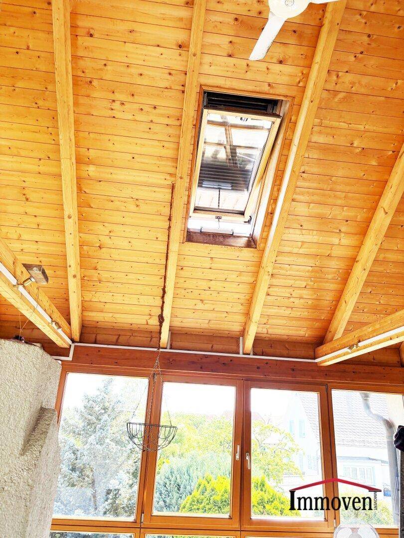 Holzverkleidete Decke mit einem Dachfenster und einem Deckenventilator für angenehmes Klima.
