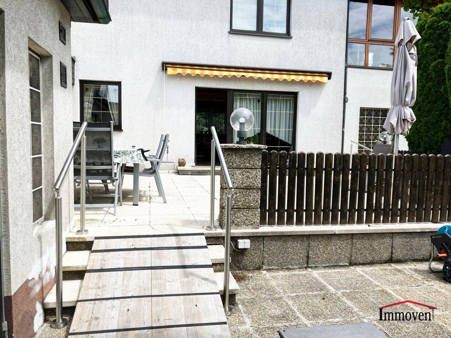Terrasse mit Zugang über eine Holzrampe und Sitzgelegenheiten im Freien.