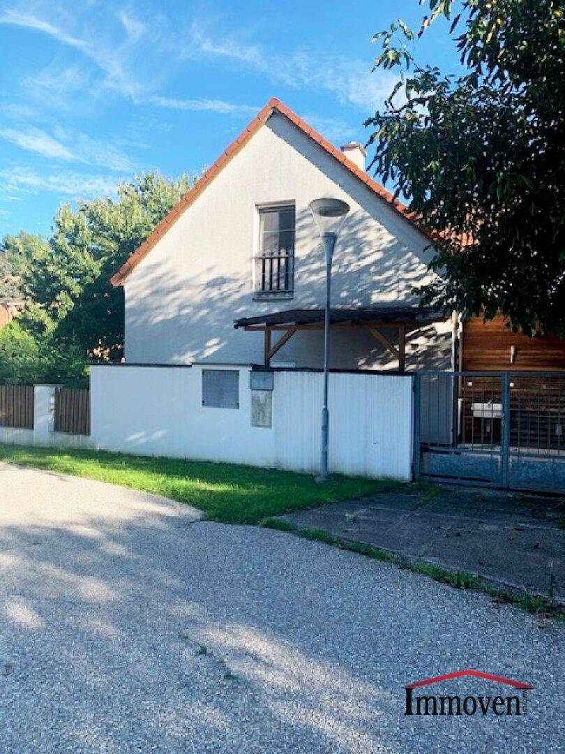 Seitenansicht des Hauses mit Satteldach, kleinem Balkon und Holzelementen.