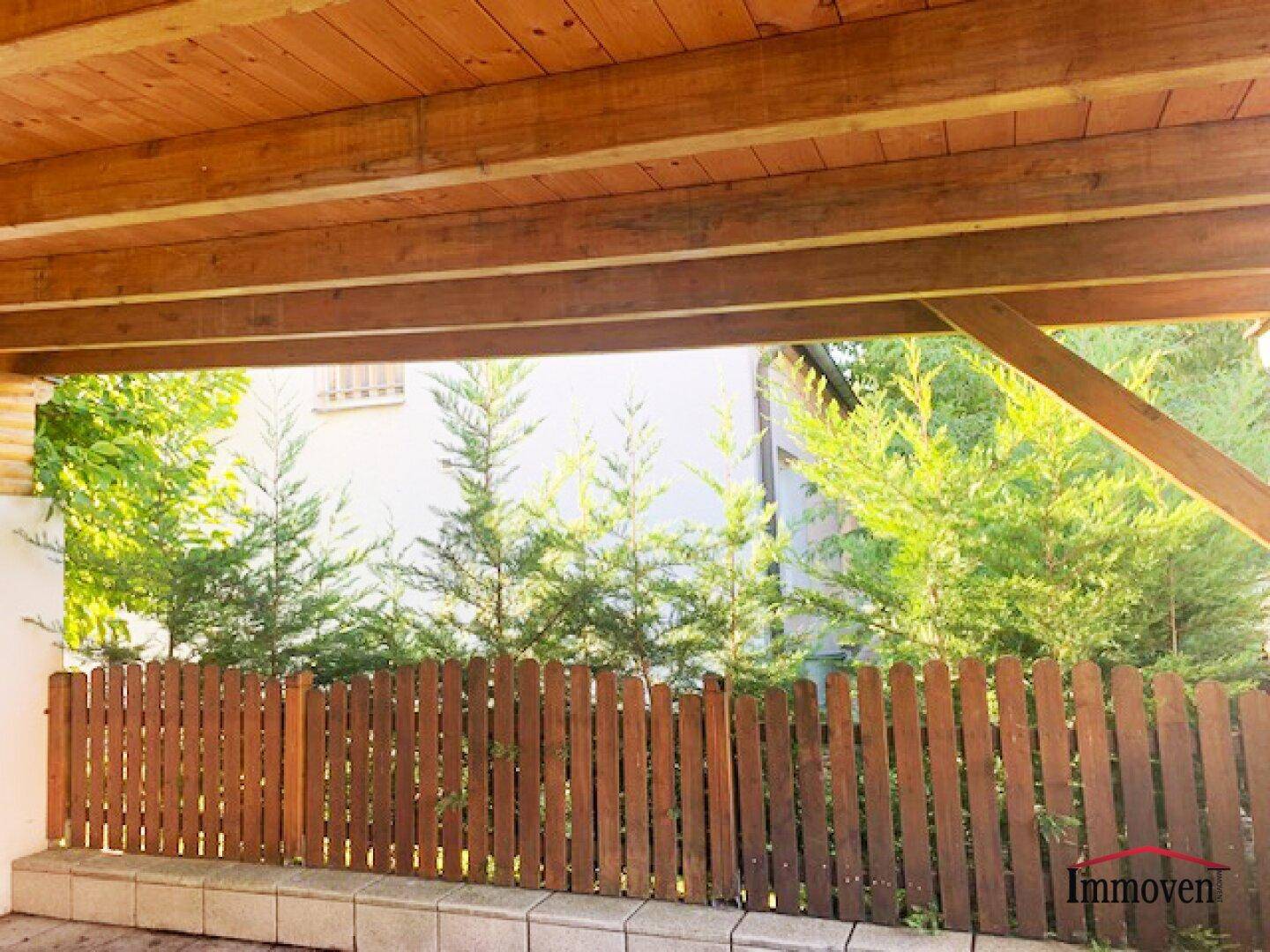 Überdachter Außenbereich mit Holzbalken und Blick auf die grüne Umgebung.