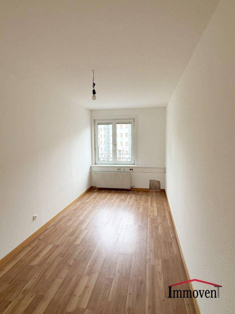 Helles Zimmer mit Holzboden und Fenster, bietet Potenzial für verschiedene Nutzungen.