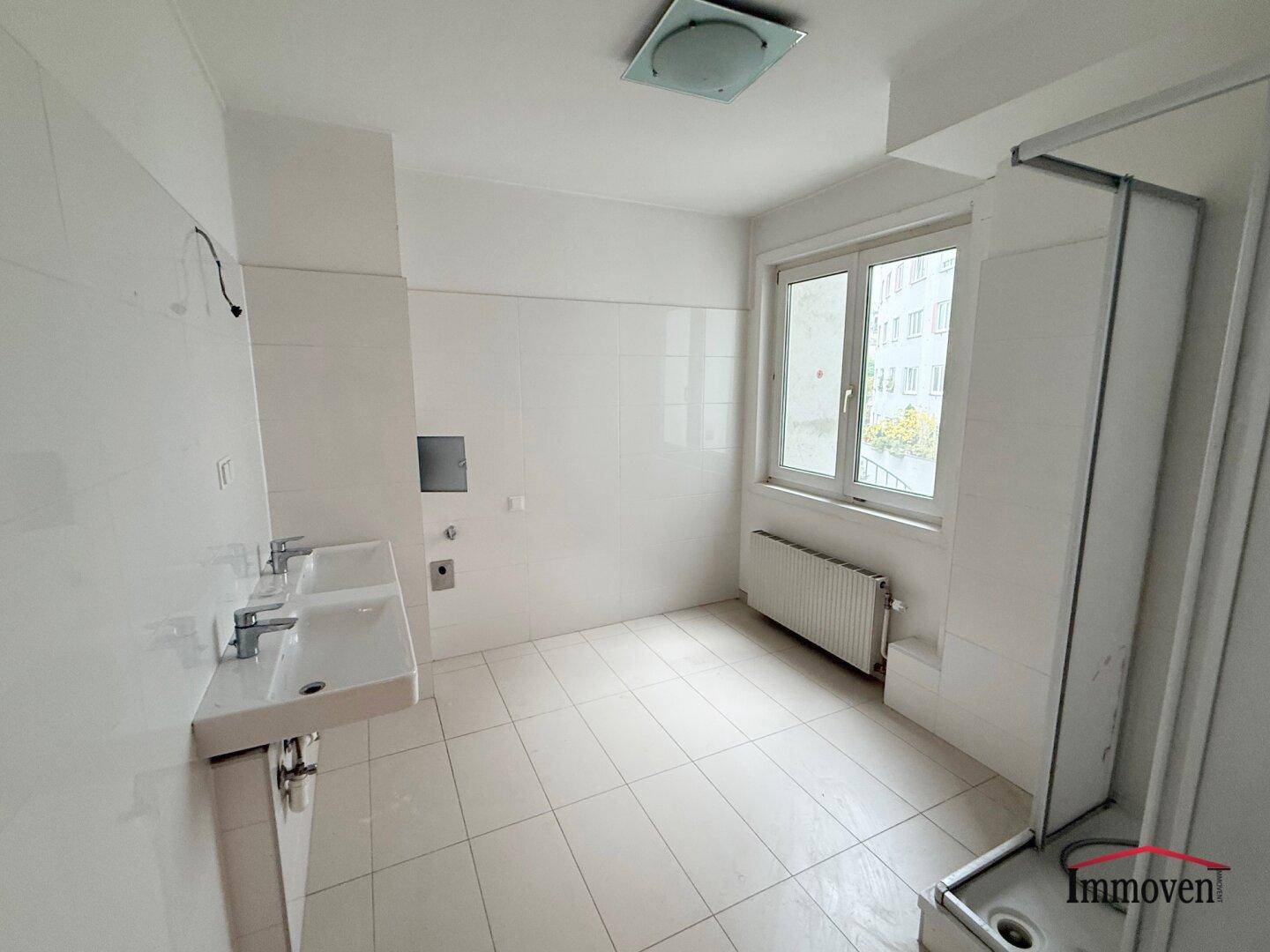 Geräumiges Badezimmer mit zwei Waschbecken, Dusche und Fenster.