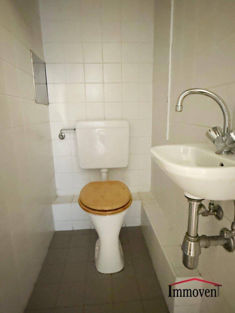 Einfaches WC mit Toilette und Waschbecken, funktional und sauber.