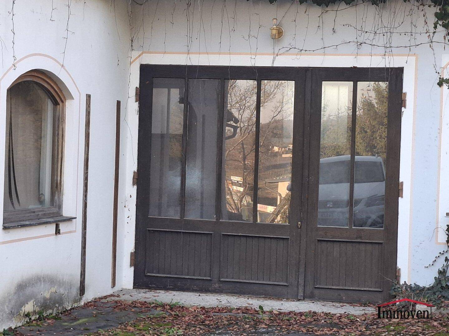 Nahaufnahme einer breiten, dunklen Holztür mit Glaspaneelen, die als Eingang zu einem Werkstattbereich dient.