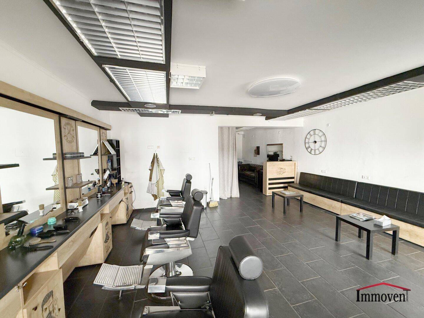 Ansicht des Friseursalons mit bequemen Stylingstühlen und einer langen Sitzbank für wartende Kunden.