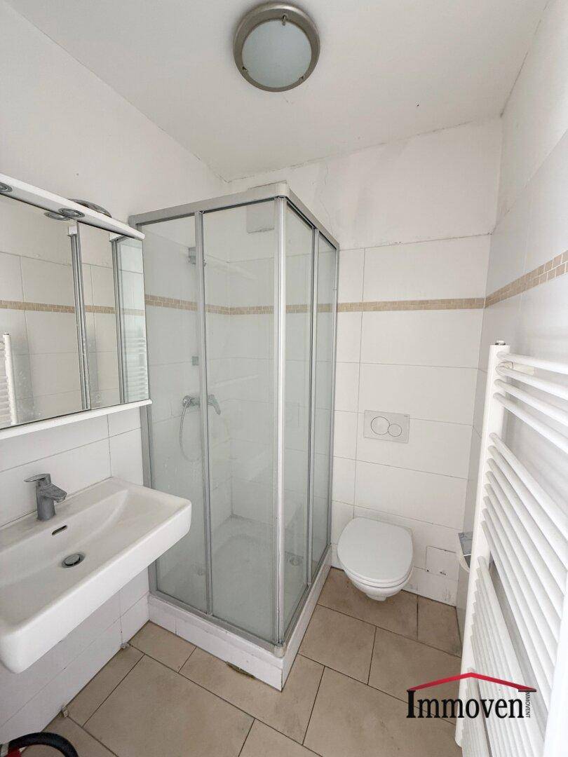 Funktionales Badezimmer mit Duschkabine, WC, Waschbecken und weiß gefliesten Wänden.