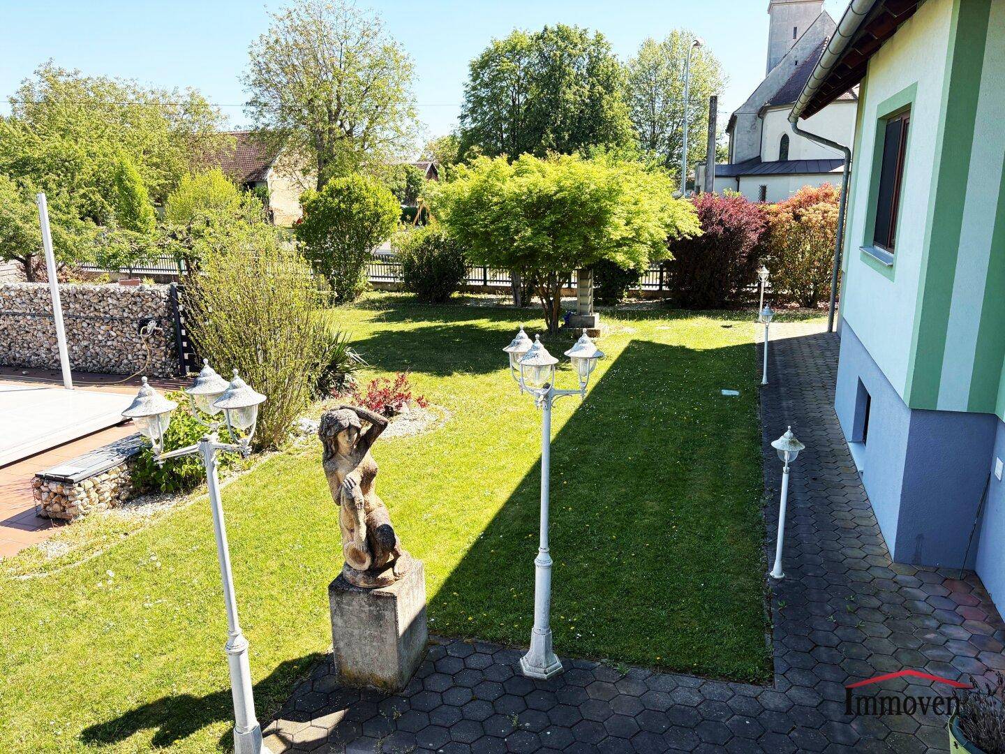 Großer, gepflegter Garten mit Rasenfläche, Bäumen und dekorativen Laternen.