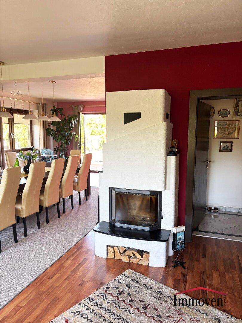 Moderner Kamin als Raumteiler zwischen Wohn- und Essbereich mit Holzparkett.