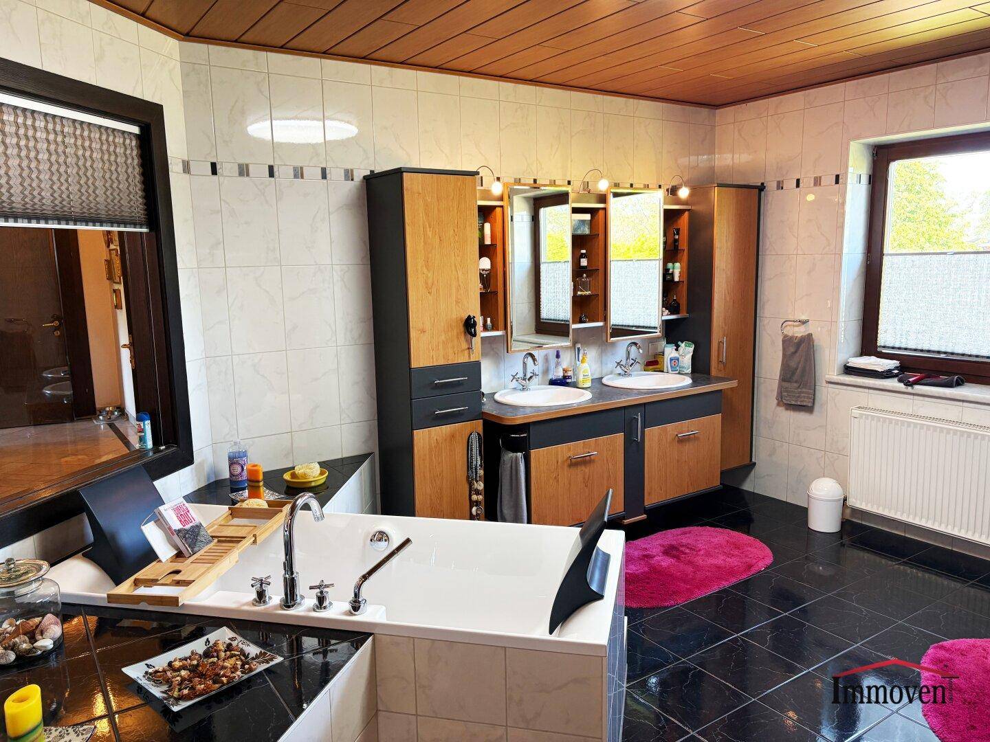 Geräumiges Badezimmer mit Badewanne, Doppelwaschbecken und Holzdecke.