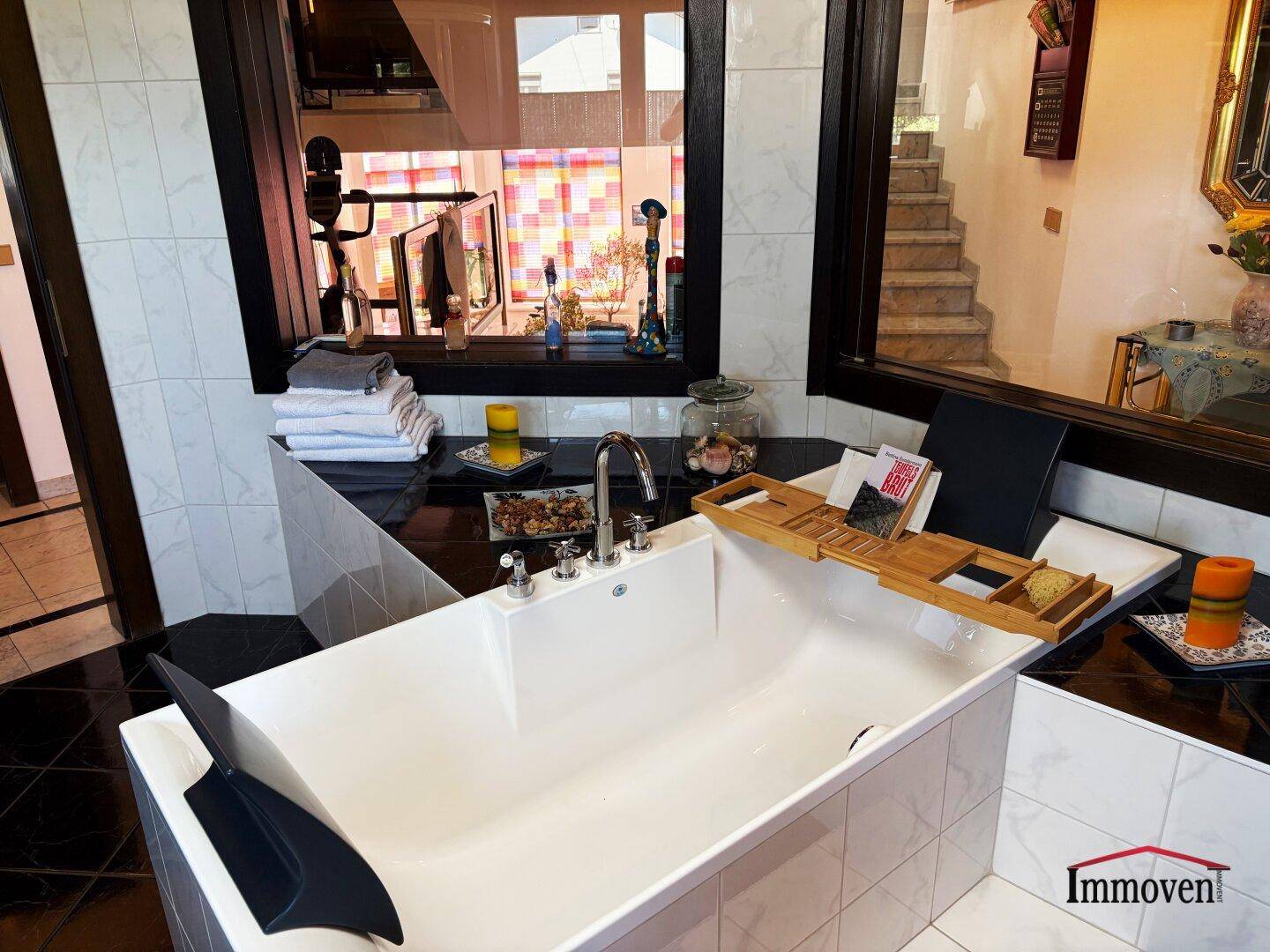 Elegante Badewanne mit Armaturen und Blick durch ein Fenster in den Flur.