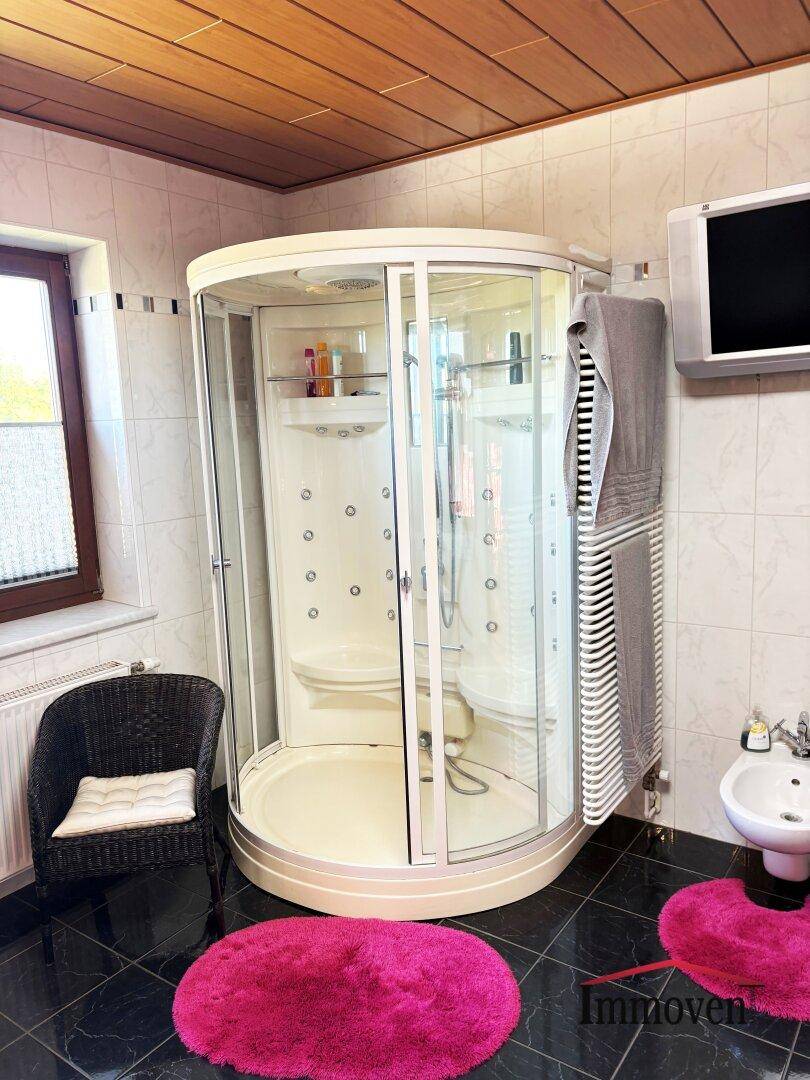 Badezimmer mit moderner Duschkabine, Bidet, beheiztem Handtuchhalter und Holzdecke.