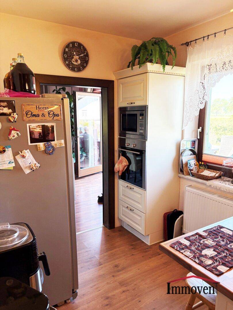 Funktionale Küche mit Einbaugeräten, Kühlschrank und Fenster mit Blick nach draußen.