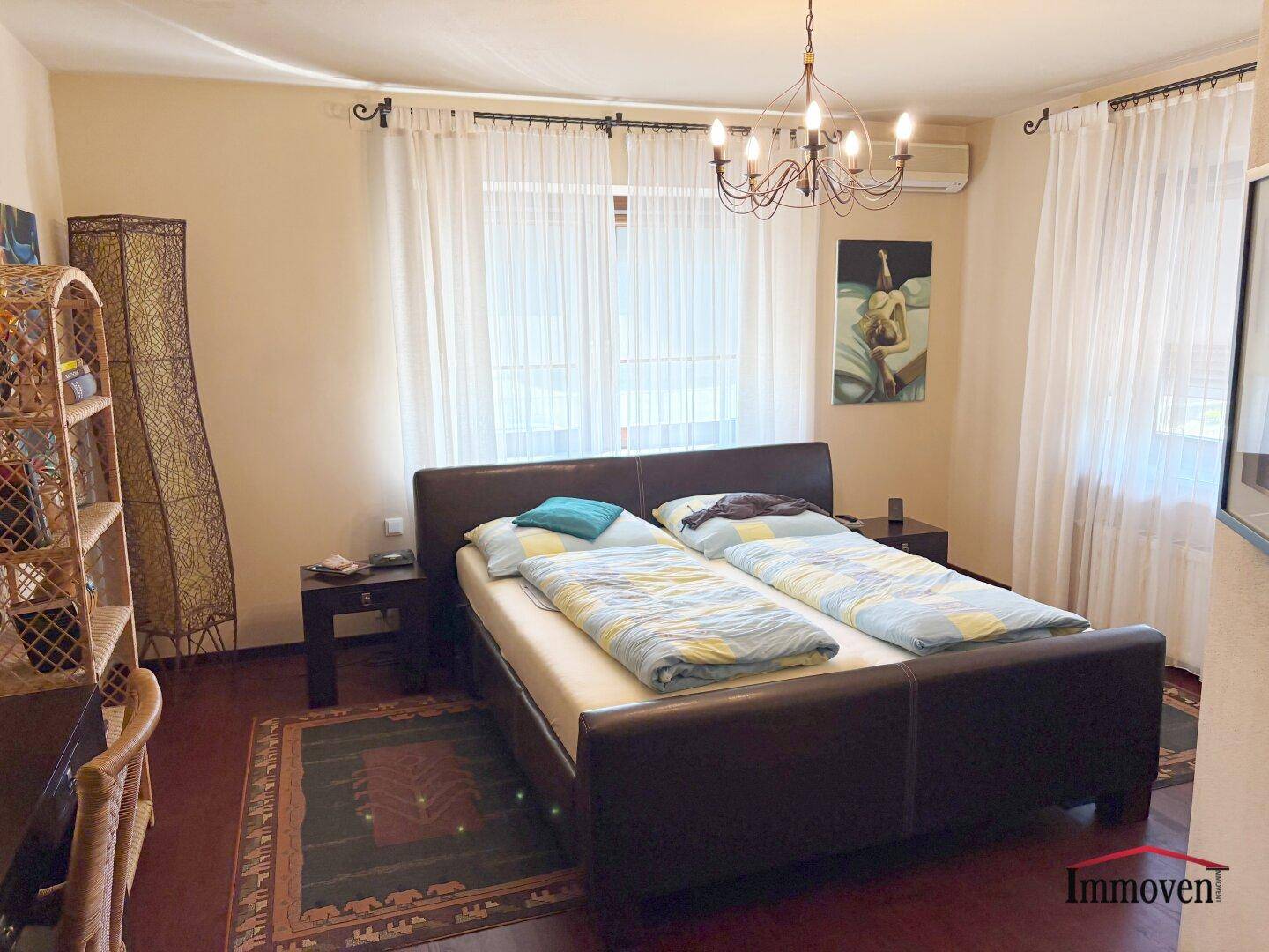 Gemütliches Schlafzimmer mit Doppelbett, dunklem Holzfußboden und Klimaanlage.